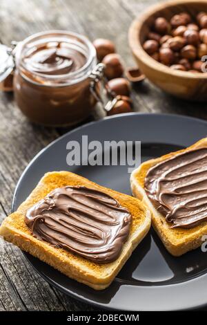 Tostare il pane con la nocciola spalmata sul piatto. Crema di cioccolato dolce. Foto Stock