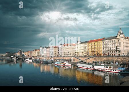 Ampia vista dal Ponte Carlo di praga sul fiume e porto con navi e case in nuvole soleggiate Foto Stock