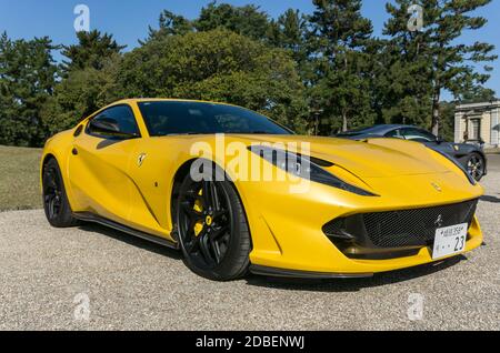 Vista frontale di una Ferrari 812 Superfast gialla con cerchi in argento brillante forgiato, all'aperto sotto il sole Foto Stock