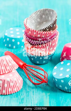 Variazione di forme di carta piccola per cuocere cupcake e muffin con wisp. Rivestimenti in carta colorati. Foto Stock