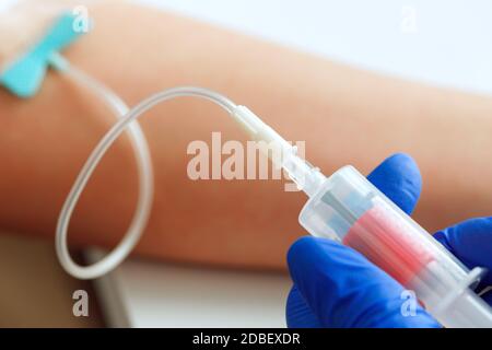 Mani di un medico che preleva campioni di sangue utilizzando una provetta supporto Foto Stock