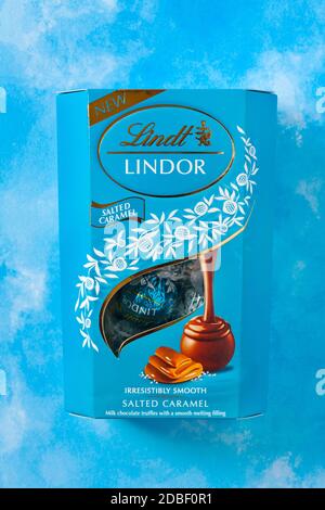 Scatola di Lindt Lindor caramello salato irresistibilmente liscio caramello salato tartufi di cioccolato al latte con un morbido ripieno di fusione sfondo blu Foto Stock