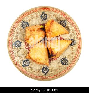 Cucina indiana - vista dall'alto del keema samosas (pasticceria salata fritta ripiena di carne e verdure) su piatto di ottone isolato su sfondo bianco Foto Stock