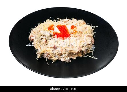 Insalata di Quail Nest servita con prosciutto, vitello e lingua di manzo, formaggio grattugiato, condita con maionese e decorata con uova di quaglia e caviale di salmone su pezzetto nero Foto Stock