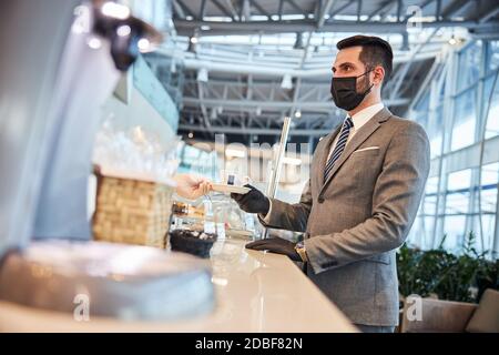 Uomo d'affari che acquista una tazza di caffè al banco Foto Stock