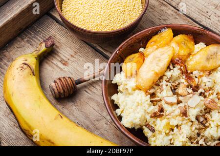 Porridge di miglio con banane caramellate e noci. Foto Stock