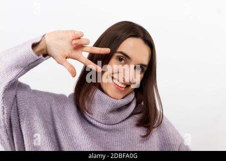 Bella giovane donna isolata su bianco mostrando due dita per la vittoria o la pace. Foto Stock