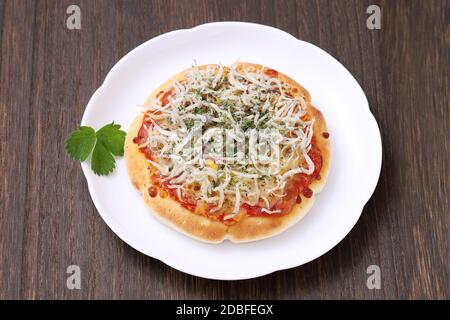 piccola pizza di shirasu di pesce su un piatto con tavolo di legno