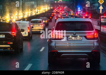 Varsavia, Polonia - 23 dicembre 2019: Traffico e tempo piovoso sulla strada in città. Riflessi di luce su superfici bagnate. Foto Stock