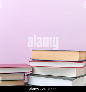 Pile di libri diversi su uno sfondo rosa primo piano. Libri di copertina rigida in diversi colori. In alto c'è uno spazio libero per l'iscrizione, il testo Foto Stock