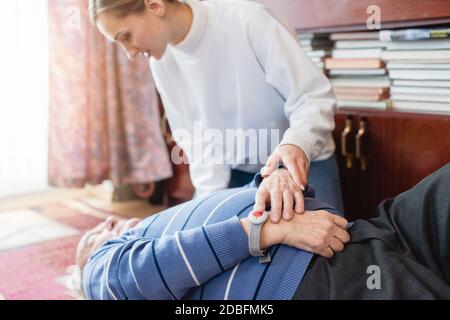 Infermiera nell'assistere il programma vivente che trova l'uomo anziano che si trova sopra il pavimento Foto Stock