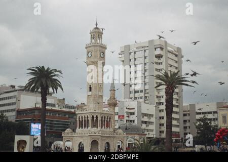 Izmir, Turchia - 16 novembre 2020 Film scan con qualche granello della Torre dell'Orologio di Konak con alcune persone e piccioni volanti. Foto Stock