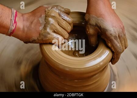 Ceramica - mani bagnate esperte di ceramica che modellano l'argilla sulla ruota di ceramica. Vaso, vaso che lancia. Produzione artigianale tradizionale indiano ciotola, vaso, pentola Foto Stock