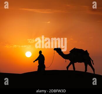 Rajasthan viaggio sfondo - cameleer indiano (camel driver) con profilo cammello nelle dune del deserto di Thar al tramonto. Jaisalmer, Rajasthan, India Foto Stock