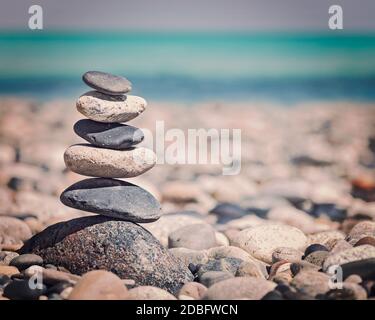 Zen meditazione sfondo - effetto retrò vintage filtrato stile hipster immagine di pietre equilibrate impilate da vicino sulla spiaggia di mare Foto Stock