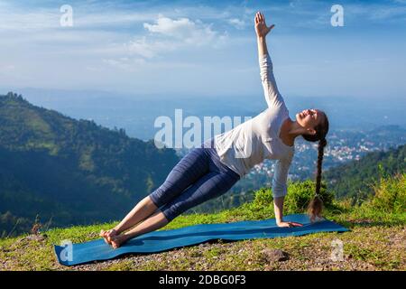 Yoga all'aperto - bella donna sportiva in forma che fa yoga asana Vasissthasana - asse laterale posa in montagna Foto Stock