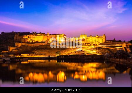 Punto di riferimento indiano - Amer Fort (Amber Fort) illuminato di notte - una delle attrazioni principali a Jaipur, Rajastan, India redelcting nel lago di Maota in tw Foto Stock