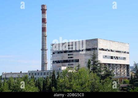 Una vecchia fabbrica sovietica con un tubo. Abbandonata l'industria sovietica. Foto Stock