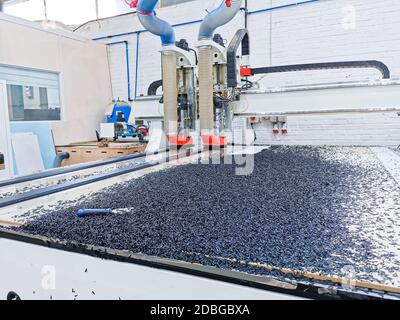 Vista di una macchina CNC che taglia attraverso un pannello di polietilene in uno stabilimento di produzione di plastica. Foto Stock