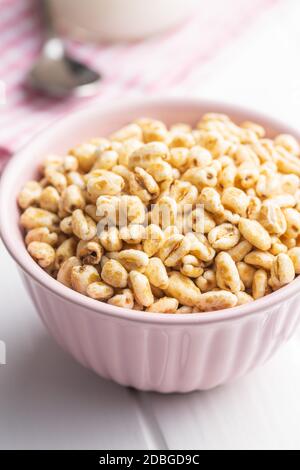 Grano soffiato coperto di miele in ciotola su tavola bianca. Foto Stock