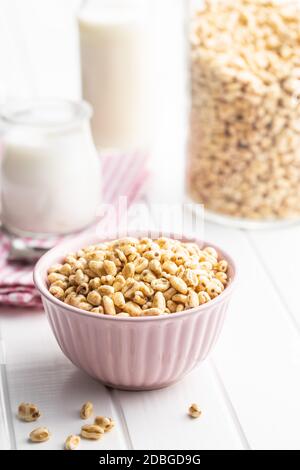 Grano soffiato coperto di miele in ciotola su tavola bianca. Foto Stock