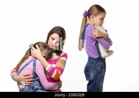 I bambini hanno litigato sui giocattoli, la mamma rassicura la figlia più giovane Foto Stock