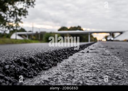 Un grande strato di asfalto caldo fresco. Strato di materia prima di asfalto in una profondità di campo poco profonda. Rulli rollin fresco asfalto caldo sulla nuova strada. Strada Foto Stock