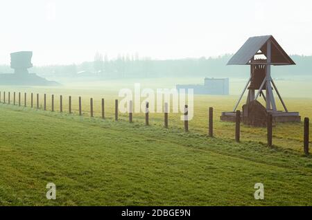 Campo di erba con recinto di filo spinato e campana di pace nel campo tedesco di concentramento e sterminio Majdanek. Lublino, Polonia Foto Stock