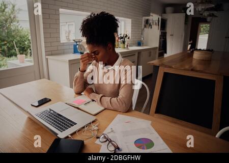 Donna giovane e frustrata che lavora a casa davanti al notebook soffrire di mal di testa Foto Stock