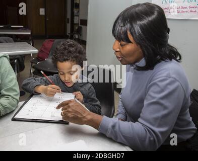 L'insegnante aiuta gli studenti delle scuole elementari a lavorare sull'ortografia delle parole in un programma post-scolastico presso un centro di Manhattan, New York City. Foto Stock