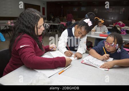 L'insegnante aiuta gli studenti delle scuole elementari a lavorare sull'ortografia delle parole in un programma post-scolastico presso un centro di Manhattan, New York City. Foto Stock