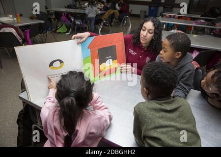 L'insegnante lavora con gli studenti delle scuole elementari per leggere le parole in un programma post-scolastico presso un centro di Manhattan, New York City. Foto Stock