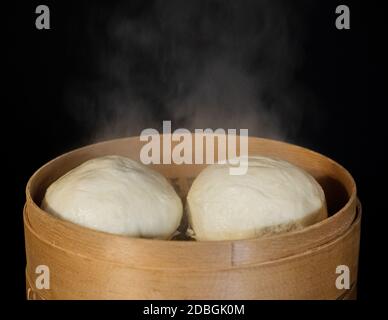 Vapore che sale da focacce cotte in cesto di bambù vaporiera Foto Stock