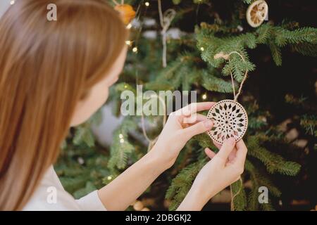 Primo piano di donna che decorano l'albero di natale con giocattolo di Natale mestiere. Concetto di vacanza invernale. Foto Stock