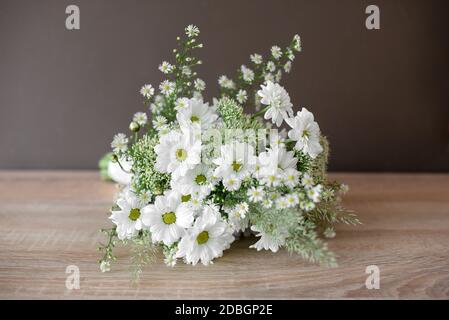 Bouquet nuziale con margherite fresche bianche di primavera su cui giace un tavolo di legno in primo piano Foto Stock