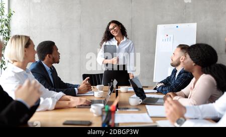 Businesswoman messicana che presenta l'idea di avvio ai colleghi nell'ufficio moderno Foto Stock