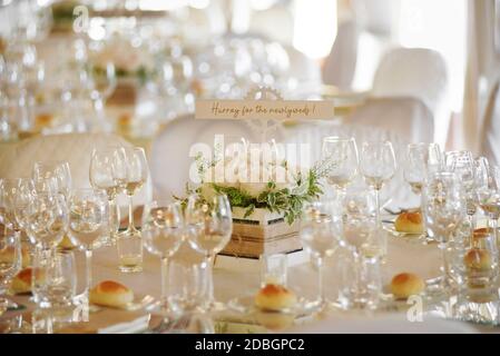 Luogo per matrimoni con tavoli formali con eleganti vetreria e. il piccolo pane rotola attorno a un centropiece con un messaggio scritto a mano Foto Stock