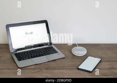 Adelaide, Australia - 7 luglio 2019: Google Home Mini con computer portatile HP con Windows 10 e telefono cellulare impostato sul tavolo accanto l'uno all'altro Foto Stock