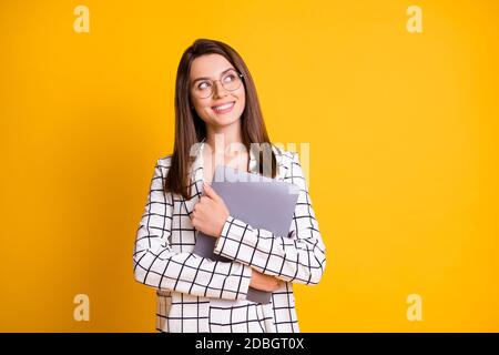 Ritratto fotografico di ragazza sognante che tiene il computer hugging guardando spazio vuoto sorridente isolato su sfondo giallo luminoso Foto Stock