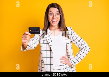 Ritratto fotografico di una donna d'affari entusiasta che dimostra carta di plastica della banca isolato su sfondo giallo brillante Foto Stock