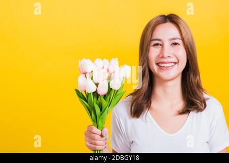 Ritratto Asian Thai bella felice giovane donna sorridente, urlando eccitato tenere fiori tulipani bouquet in mani e guardando alla fotocamera, studio girato iso Foto Stock