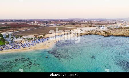 Vista aerea del tramonto sulla costa e della spiaggia simbolo di Agia Thekla, Ayia Napa, Famagosta, Cipro dall'alto. Vista dello skyline dall'alto dell'attrazione turistica Foto Stock