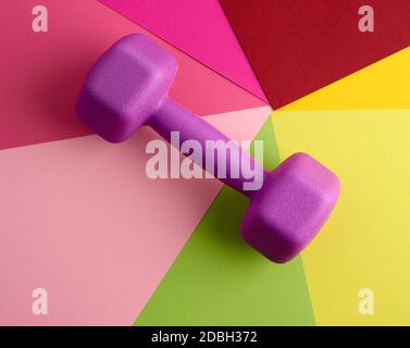 gnobbell in plastica viola per sport su sfondo a colori, primo piano. Attrezzature per il sollevamento pesi. Allenamento fitness. Stile di vita sano Foto Stock