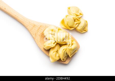 Tortellini su cucchiaio di legno. Pasta ripiena italiana isolata su sfondo bianco. Foto Stock