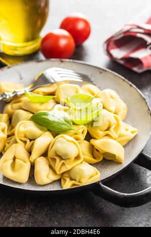 Tortellini. Pasta ripiena italiana con foglie di basilico su padella. Foto Stock