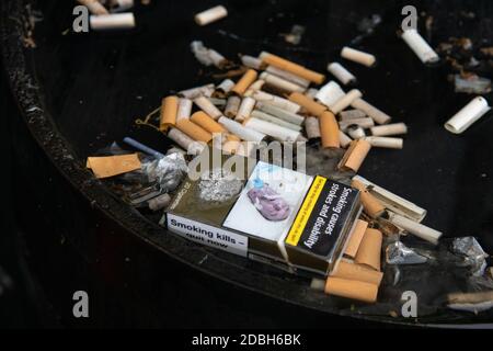 Sigarette - Tute di sigaretta e pacchetto vuoto con avvertenze per la salute - in acqua piovana in cima al whisky barile fuori pub - Scozia, Regno Unito Foto Stock