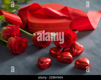 Cuori rossi cioccolatini di fronte di rose rosse e hart scatola sagomata. Il giorno di San Valentino concetto Foto Stock