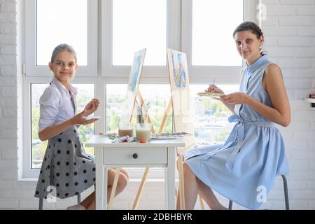 Ragazza e ragazza siedono dalla finestra e disegnare un'immagine, guardato nella cornice Foto Stock