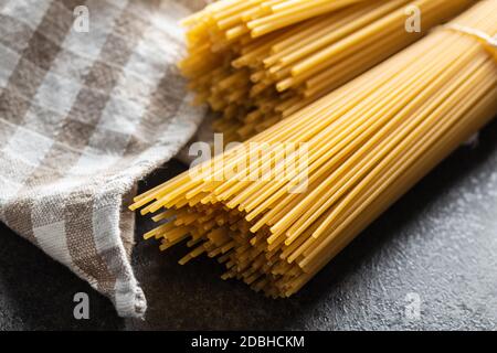 Spaghetti italiani crudi su tavola nera. Foto Stock
