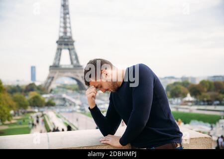 Bell'uomo che indossa un pullover blu scuro è in piedi Lo sfondo della Torre Eiffel Foto Stock